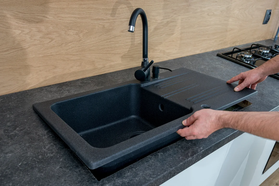 Person baut Spüle in Küche ein